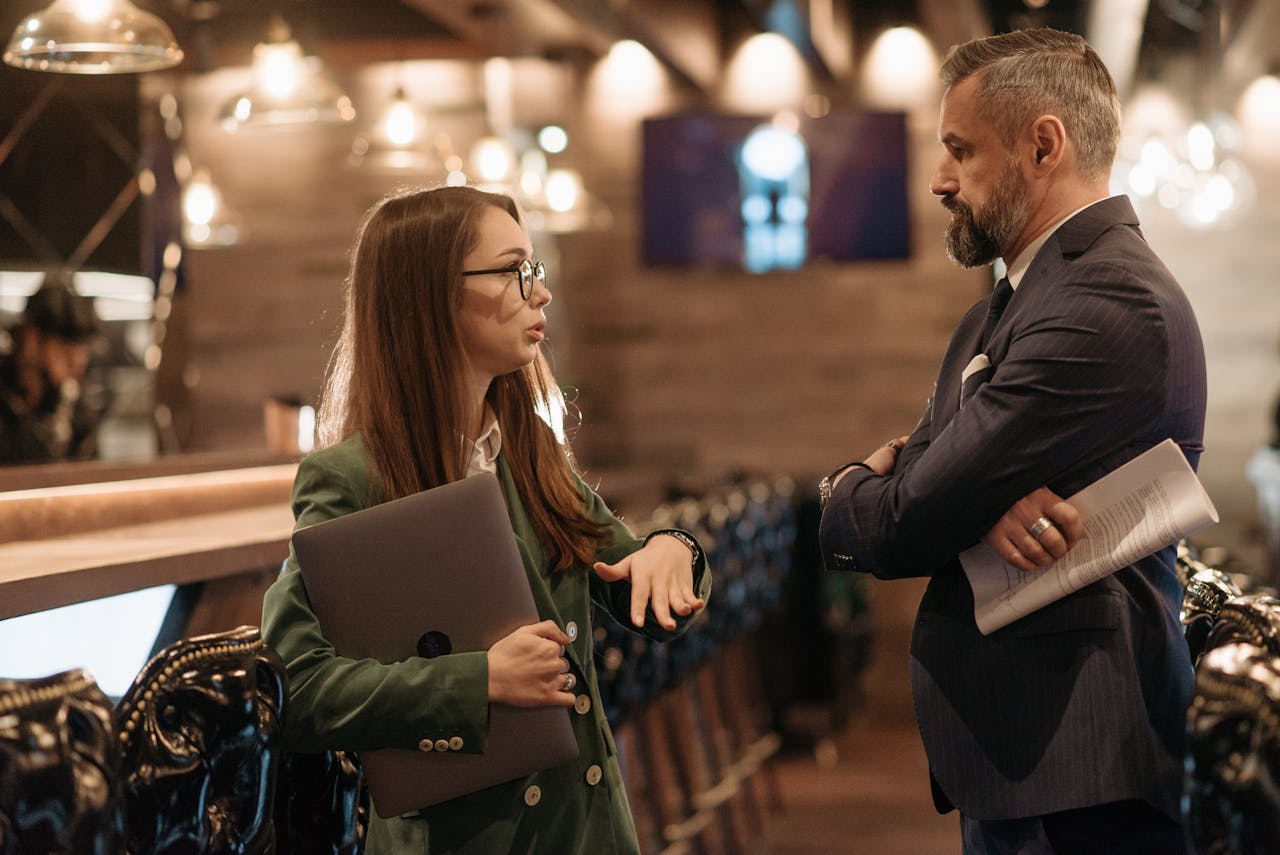 why-choose-us Two business professionals engaging in conversation in a stylish bar interior, highlighting modern work culture.